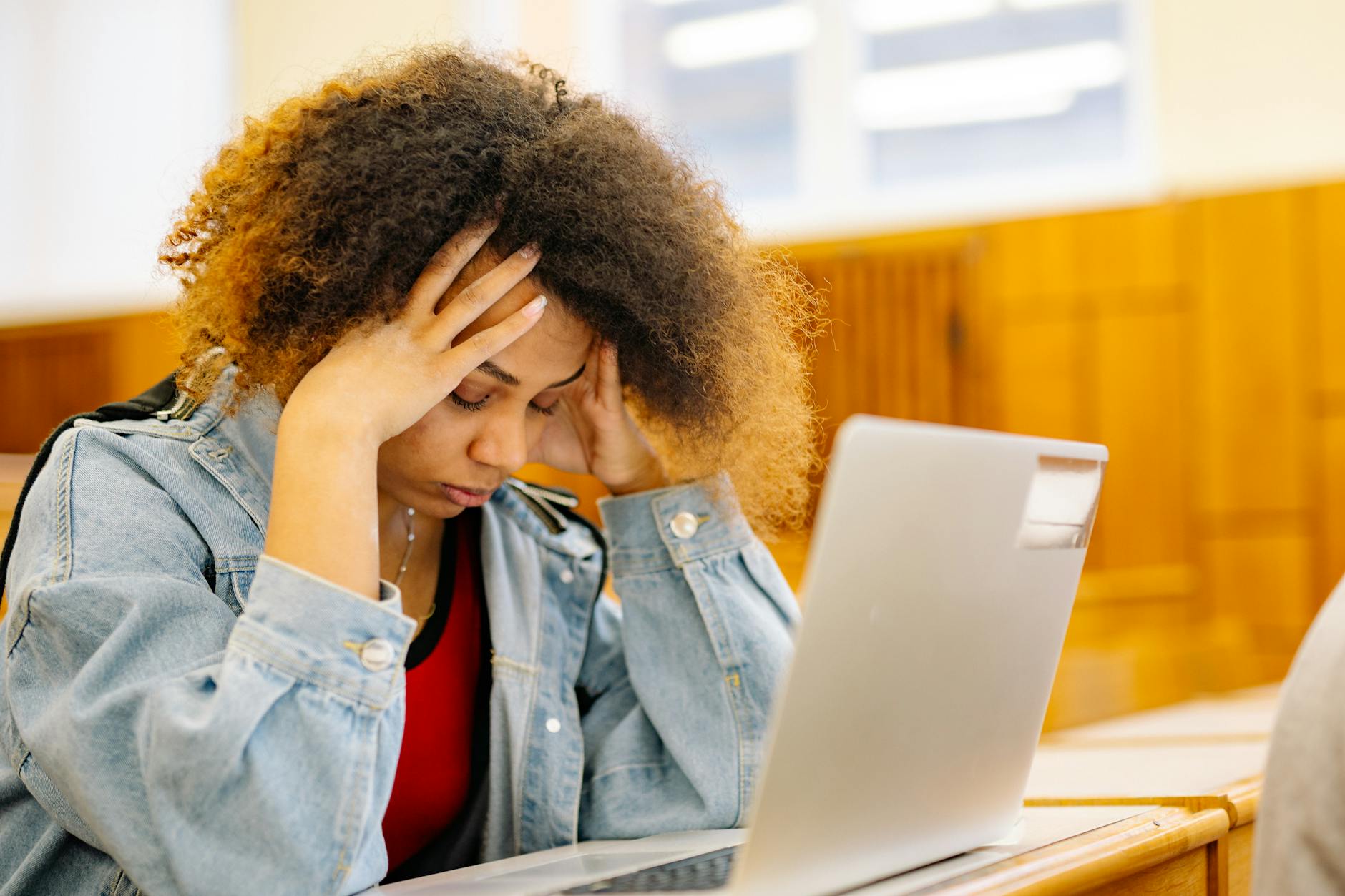 Zestresowana studentka z bólem głowy przy laptopie podczas nauki