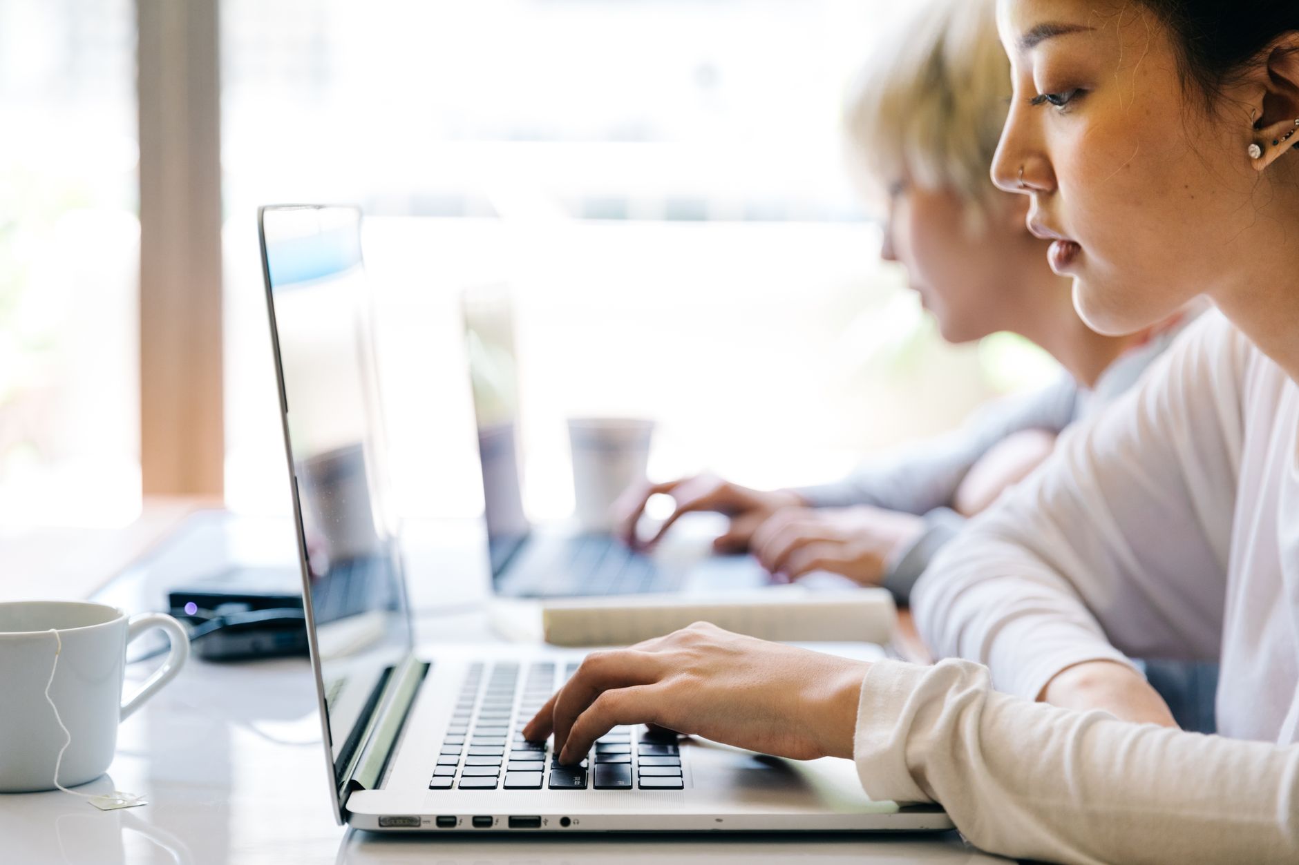 Młodzi azjatyccy nauczyciele pracują przy laptopie w nowoczesnej sali