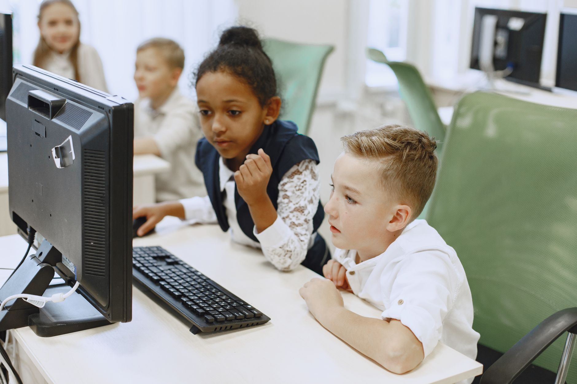 Uczniowie przy komputerach w nowoczesnej klasie korzystają z narzędzi online