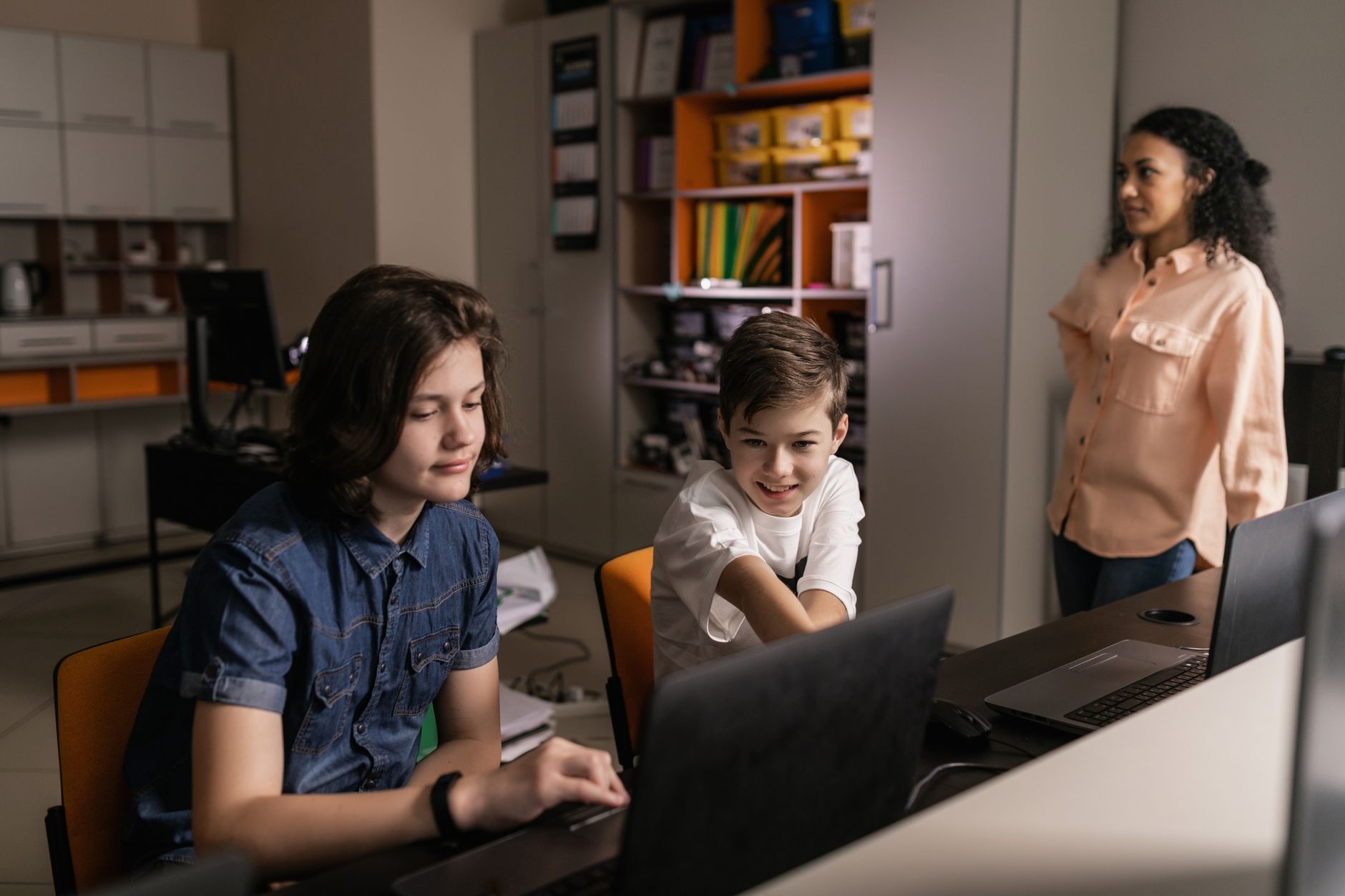 Chmura w szkole: najlepsze narzędzia online do współdzielenia plików i projektów Uczniowie z laptopami w klasie, nauczyciel wspiera naukę online
