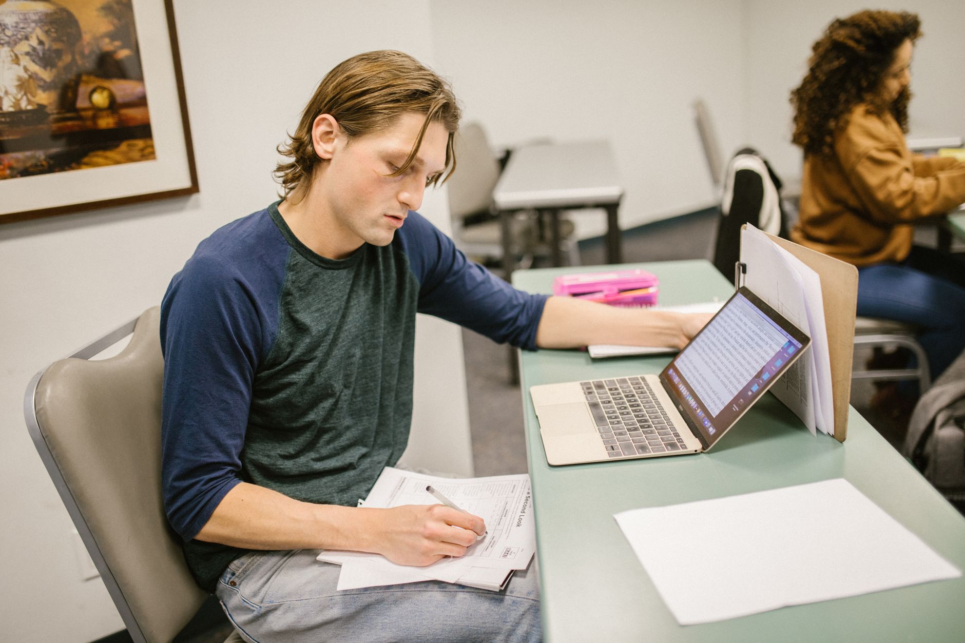 Student przy biurku analizuje notatki i pracuje na laptopie przed egzaminem