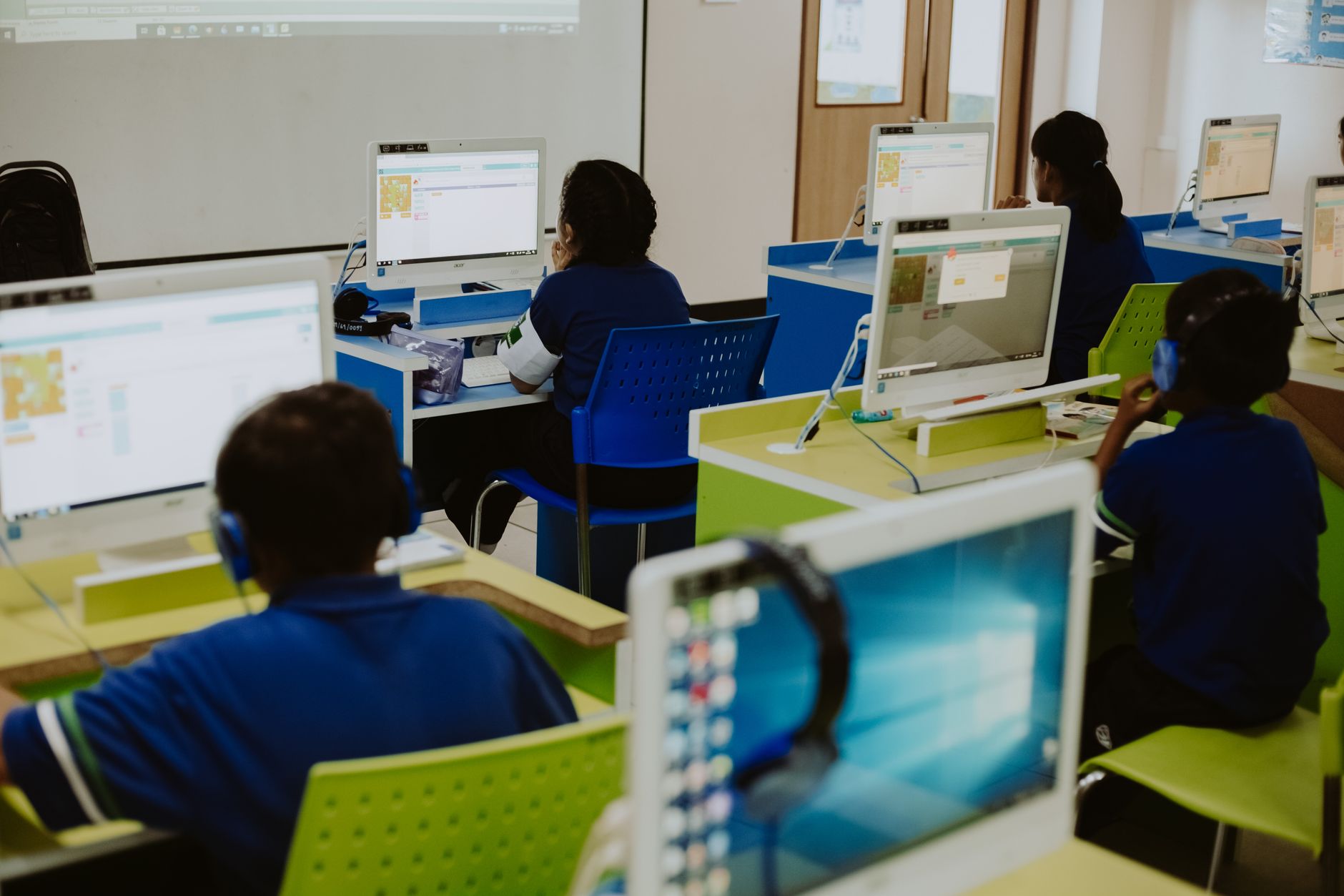 Uczniowie pracują przy komputerach w nowoczesnej pracowni informatycznej